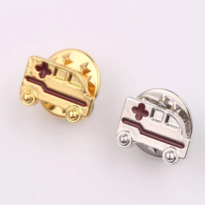 Détail de pins émaillés en forme d'ambulance or et argent avec croix rouge et fermoir