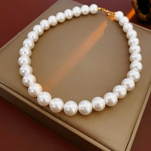 Gros plan d'un collier de perles blanches avec fermoir doré sur un coffret à bijoux