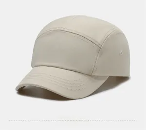 Side view detail of a beige 5-panel canvas camping cap with metal eyelets and stitching