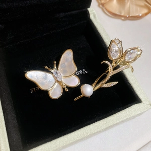 Close-up of gold-plated tulip and butterfly brooches with shell and zircon inlay