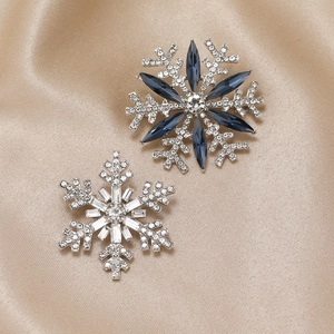 Detailed close-up of two snowflake brooches with silver and blue rhinestones on silk