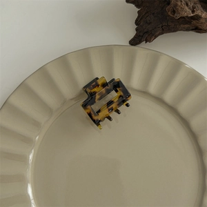 Detailed view of a medium tortoise shell acetate hair claw clip on a ceramic dish