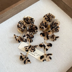 Detailed macro view of leopard print fabric flower earrings with golden metal tassels