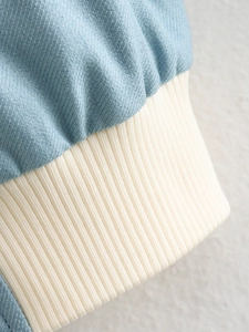 Close-up of contrast denim fabric and ivory ribbed knit cuff on bomber jacket
