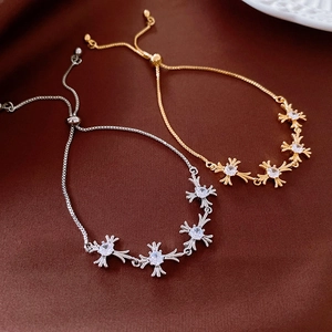 Detail of adjustable zircon cross flower bracelets in gold and silver with box chain