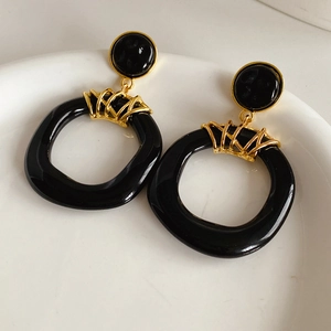 Gros plan de boucles d'oreilles vintage en résine noire sur un plateau en céramique blanc
