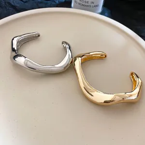Polished wavy open bangles in gold and silver finish with minimalist metal design
