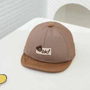 Detail of breathable brown mesh baby sun hat with cute bear patch and soft cotton brim