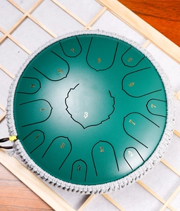 Top-down view of green steel tongue drum with woven rope edge and gold scale numbers