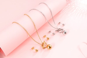 Detail of gold and silver jewelry set featuring OT buckle necklaces and ball stud earrings