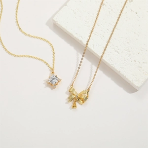 Detail of 14K gold plated necklace featuring zircon star and bowknot with bell pendant