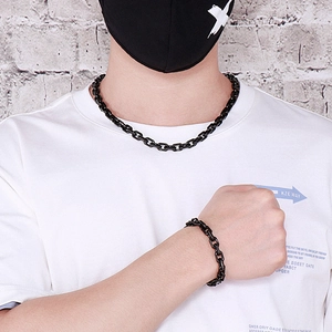Close-up of matte black stainless steel O-chain necklace and bracelet set on a model