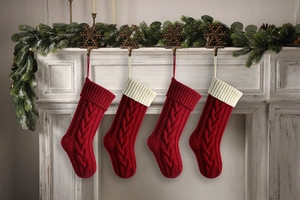 Macro detail of four red cable knit Christmas stockings with white cuffs on fireplace