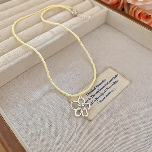 Dettaglio della collana di perline con ciondolo a fiore d'argento e zirconi in box