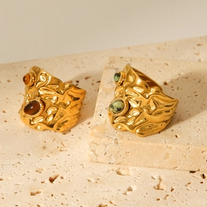 Detail of hammered gold stainless steel rings featuring tiger eye and green spotted stones