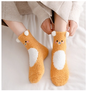 Detail of plush coral fleece warm socks with cute cartoon bear face and 3D white pom-poms
