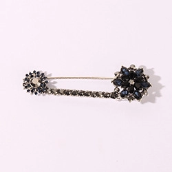 Macro shot of silver-tone dragonfly brooch featuring dark crystals and flower accents