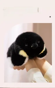 Détail d'une peluche de manchot douce tenue à la main, montrant sa texture duveteuse