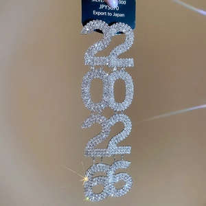 Macro shot of silver tassel earrings with glittering rhinestones in number 2026 pattern