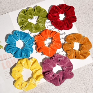 Set of seven colorful velvet hair scrunchies arranged in a circle for retro fashion