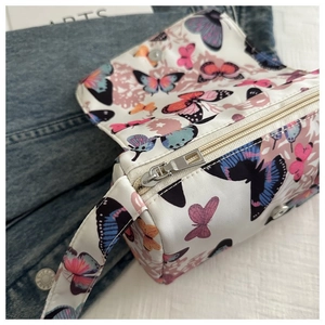 Detail of white butterfly print crossbody bag with zipper closure and wide strap