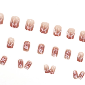 Faux ongles dégradé rose avec lignes de fleurs blanches et perles élégantes