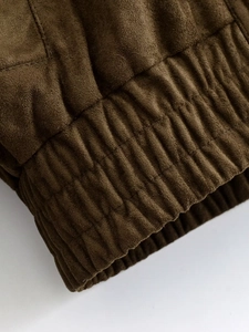 Détail d'une veste en daim marron foncé avec poignet élastique et coutures précises
