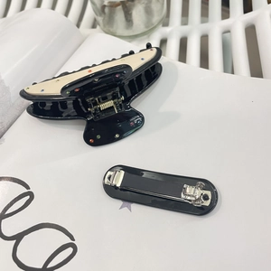 Acetate hair claw set with rhinestones and black rectangular clip on book background