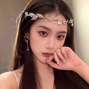 Close-up of silver leaf crown headband and heart tassel earrings with rhinestones