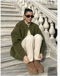 Deep green bomber jacket paired with beige pants and brown winter boots in outdoor setting