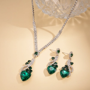 Détail de parure vintage argentée avec cristaux en forme de cœur vert et strass brillants