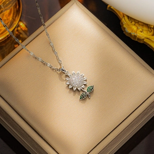 Silver sunflower pendant necklace with zircon petals and green gemstone leaves on gold satin