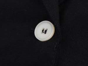 Vue macro d'un bouton blanc à quatre trous sur un tissu noir en lin mélangé