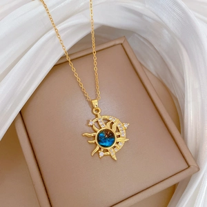 Celestial gold necklace with sun moon pendant and blue gemstone on silk fabric