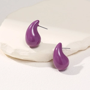 Detail view of purple teardrop earrings on minimalist white stone textured background