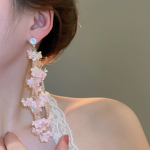 Close-up of pink floral tassel earrings with sparkling crystals worn by a model
