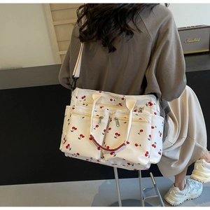 Close-up of white canvas tote bag with cherry prints and multiple functional zipper pockets