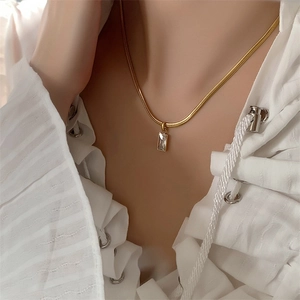 Detail of emerald green rectangular zircon necklace on a gold snake chain on skin