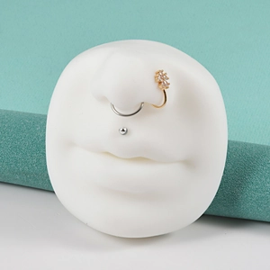 Detailed view of nose and lip piercing jewelry on a white silicone face display model