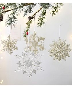 Close-up of sparkling acrylic snowflakes with glitter hanging on festive pine branches