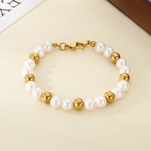Detail of beaded bracelet with white pearls and gold steel beads featuring a lobster clasp