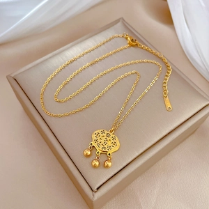 Macro detail of a gold titanium steel lock pendant necklace with bell charms and hollow pattern