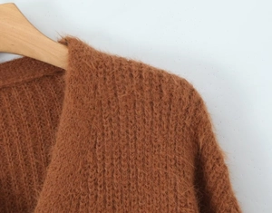 Close-up detail of soft brown mohair knit cardigan texture on a wooden hanger