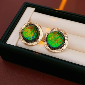 Detailed shot of golden round earrings with green opal stone in a jewelry box
