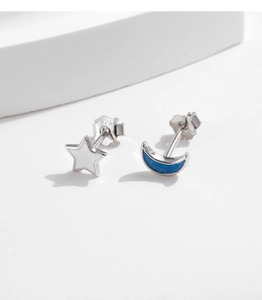 Macro view of S925 silver star and moon earrings with blue and white enamel details