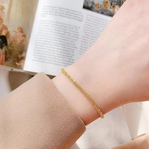 Elegant minimalist gold braided stainless steel chain bracelet worn on a female wrist