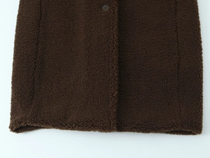 Detailed macro view of dark coffee teddy fleece fabric with thick grainy texture and seams
