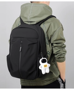 Detail view of water-resistant oxford backpack with a white astronaut plush keychain