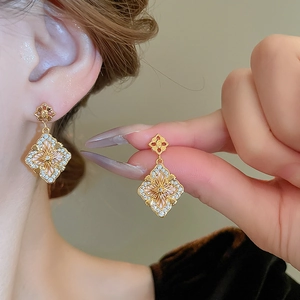 Détails de boucles d'oreilles fleur dorées avec filigrane et pierres de zircone brillantes