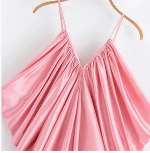 Dettaglio di canotta in raso rosa con scollo a V ed elegante trama a pieghe